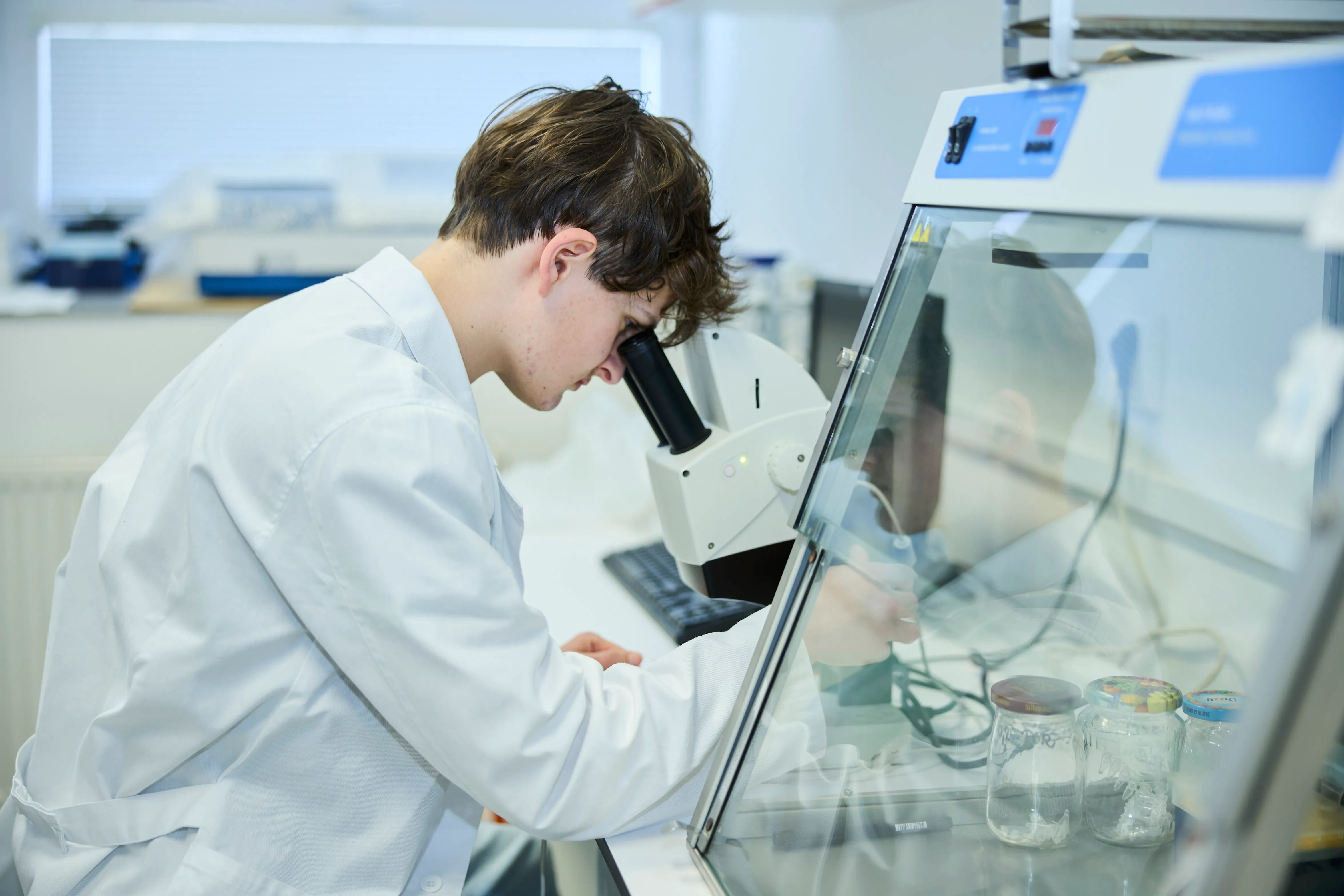 Študent skúma vzorky bakteriofágov pod mikroskopom v laboratóriu