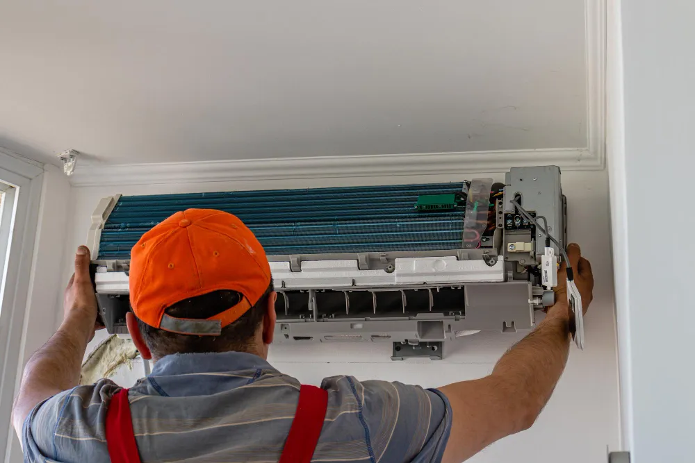 Odborník vykonáva demontáž klimatizácie zo steny.