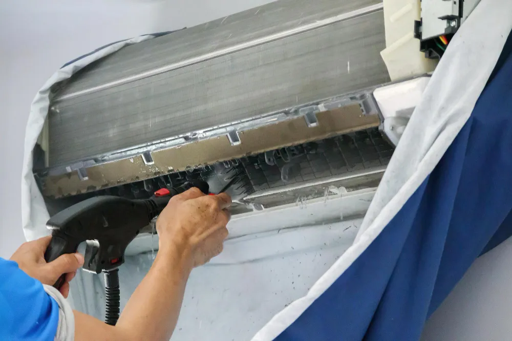 Servisný technik čistí výparník klimatizácie kefou pri odbornej dezinfekcii.