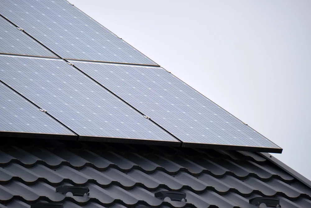 Fotovoltaické panely na šikmej plechovej streche imitujúcej škrídlu.